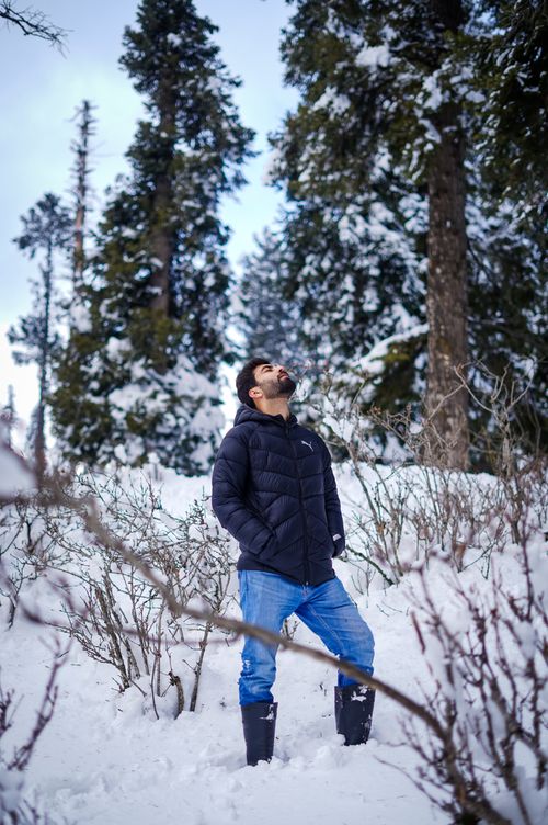 Free A man stands in a snowy forest in Yousmarg, looking up at the sky during winter. Stock Photo