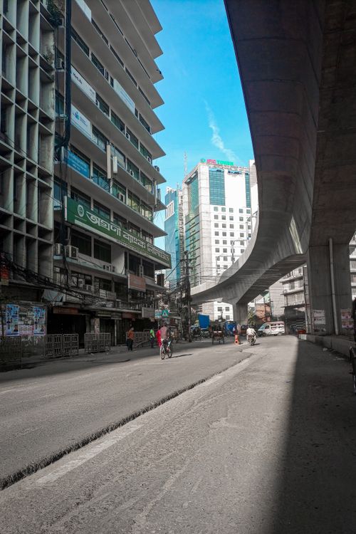 Free Street view of urban cityscape featuring an elevated bridge and modern skyscrapers under a bright blue sky. Stock Photo