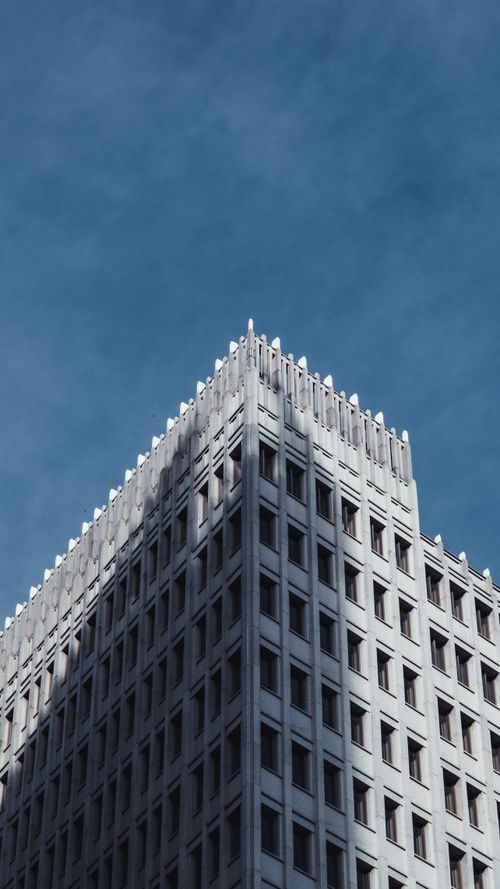 Free Low angle shot of urban high-rise building facade in Berlin with clear blue sky. Architectural perspective. Stock Photo