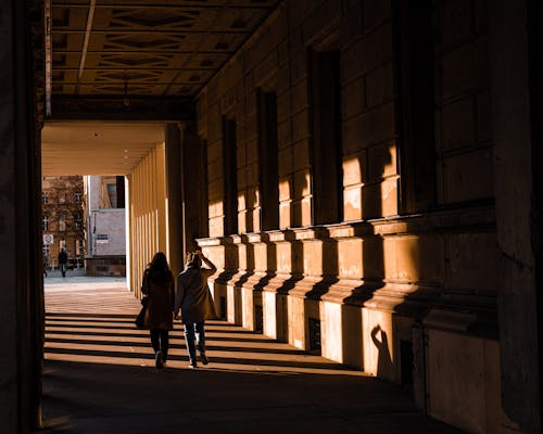 Couple Walking under Columns in Old Courtyard