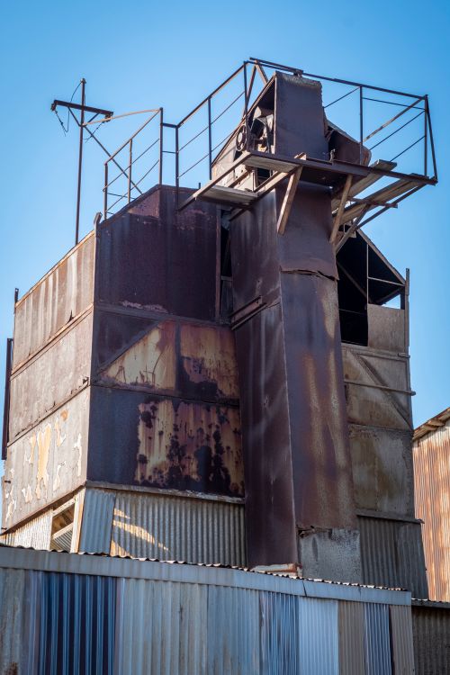 Free Rusty steel warehouse structure with blue sky backdrop, showcasing industrial decay. Stock Photo