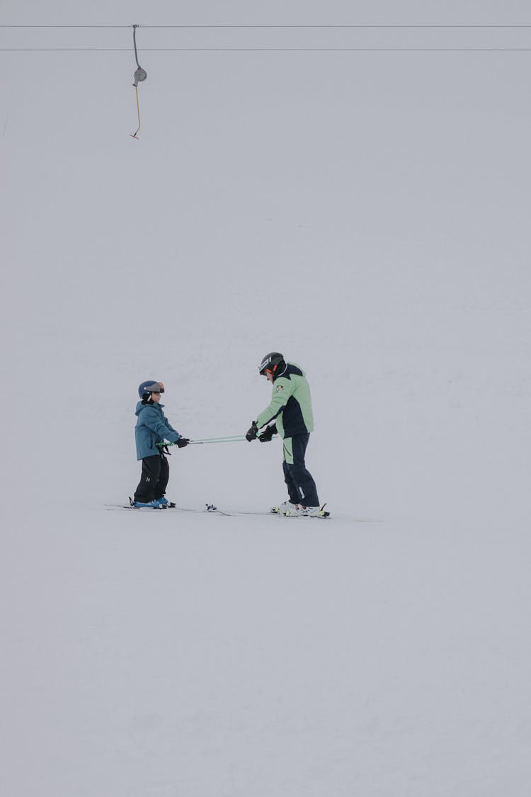 Man And Child Skiing On Snow Hill