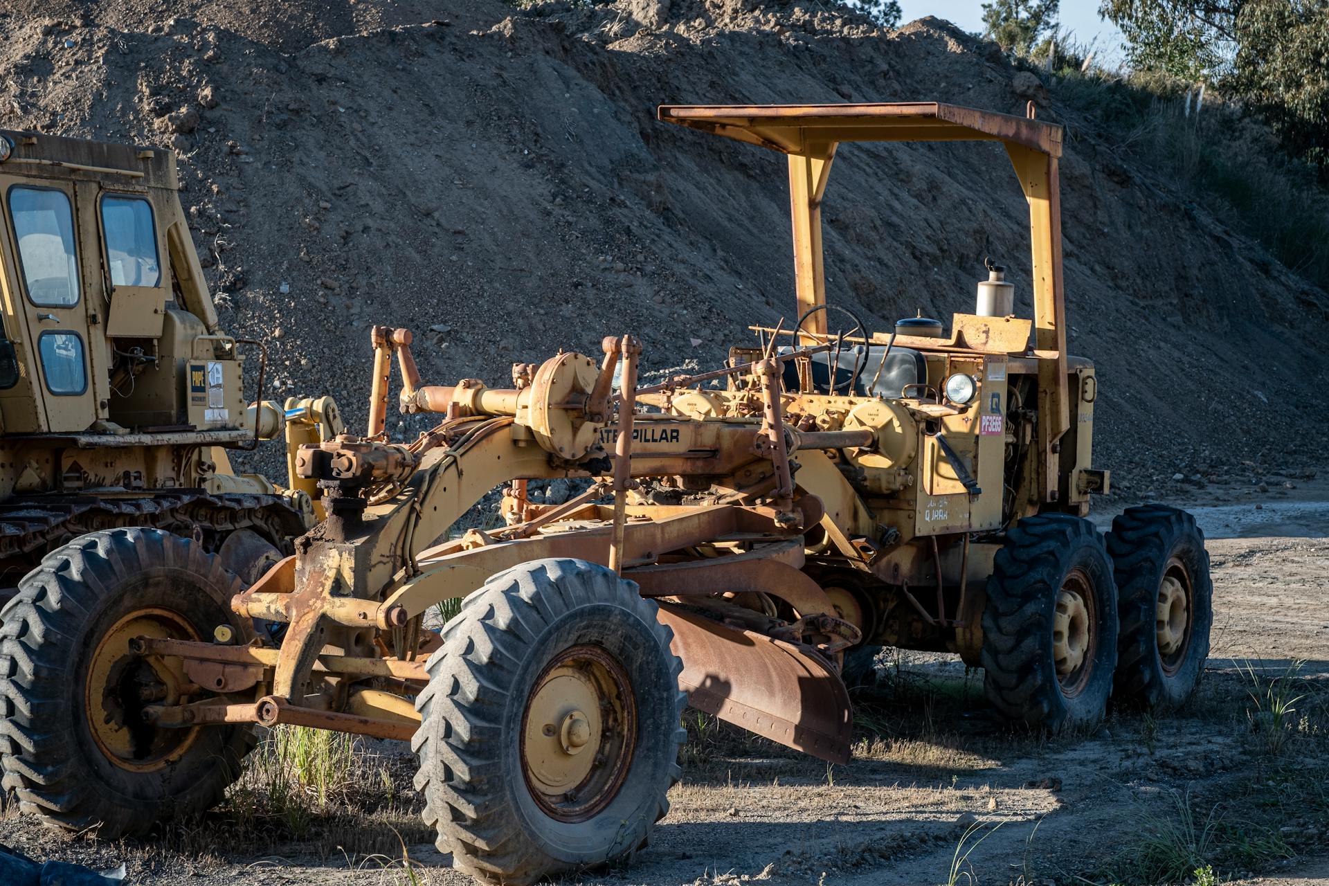 An old yellow grader at a construction site, showcasing heavy machinery in natural daylight.