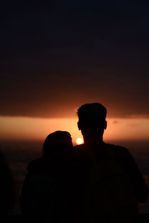 Free Silhouette of a couple embracing at sunset on the beach, conveying romance and togetherness. Stock Photo