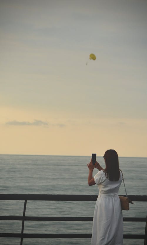 Woman Taking Pictures on Sea Shore