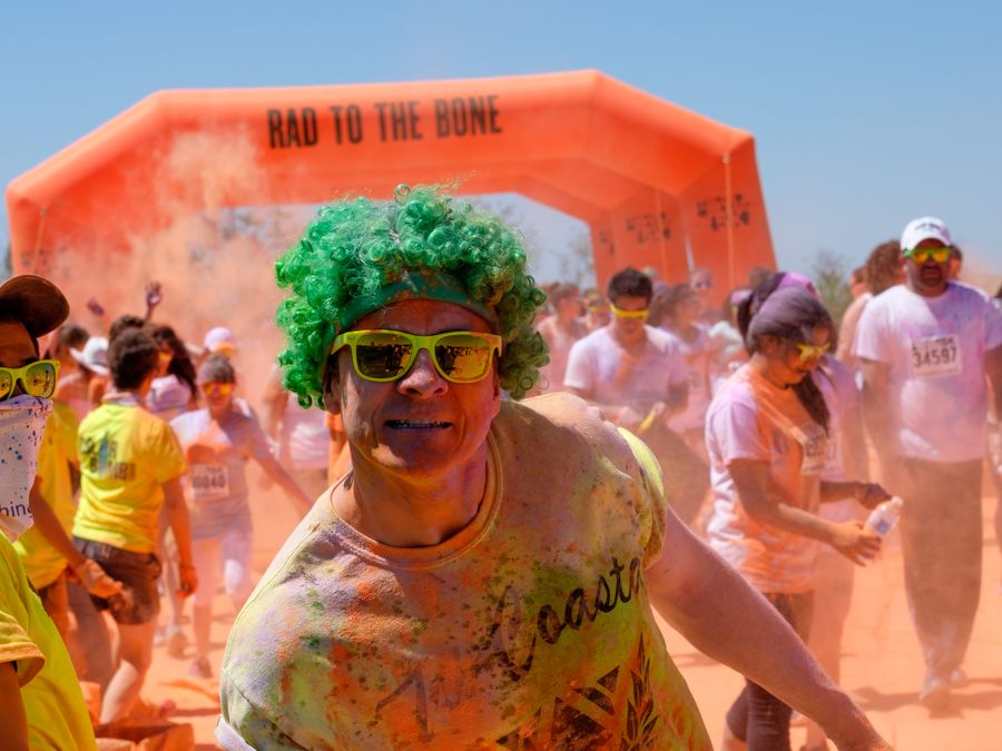 Runners covered in color powder under an inflatable arch
