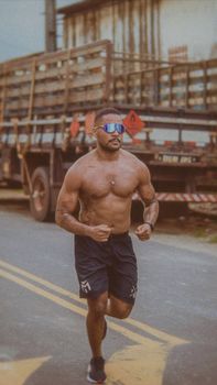 Fit man running on street in sunglasses, showcasing strength and determination.