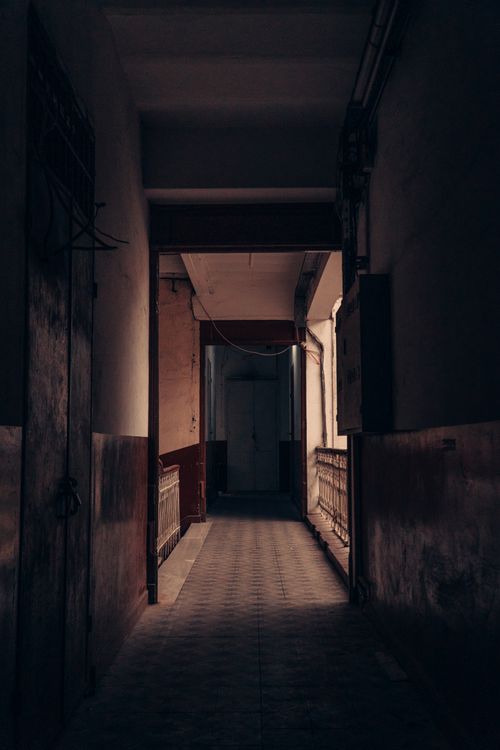Free A sunlit, empty indoor corridor featuring rustic walls and a moody atmosphere. Stock Photo