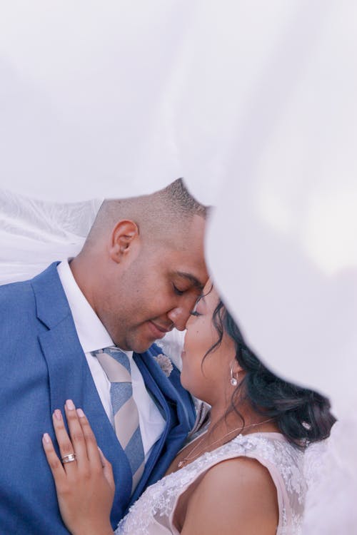 Newlywed Facing Each Other Under White Textile