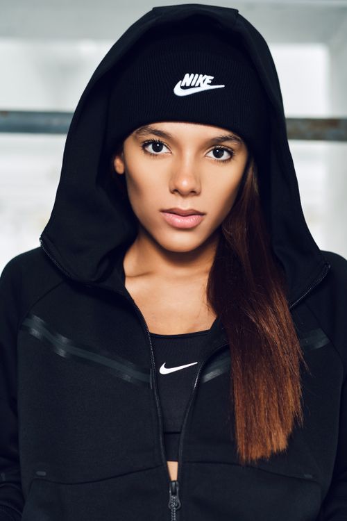 Free Portrait of a young woman in black sportswear, featuring a beanie and hoodie. Stock Photo