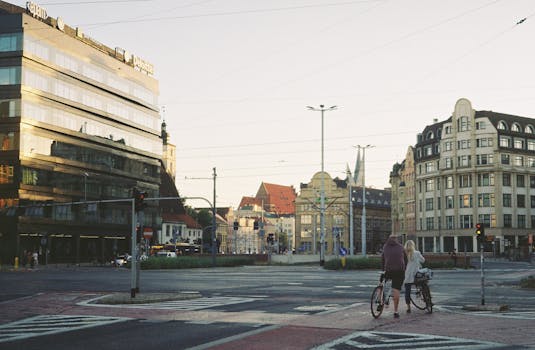 Cyclists crossing an urban intersection in Wrocław, Poland, at sunset.