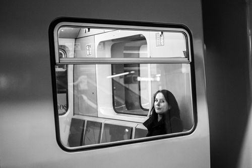 Free Black and white photo of a woman sitting on a subway train, looking thoughtful through the window. Stock Photo