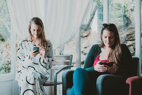 Две женщины используют смартфоны в комнате
