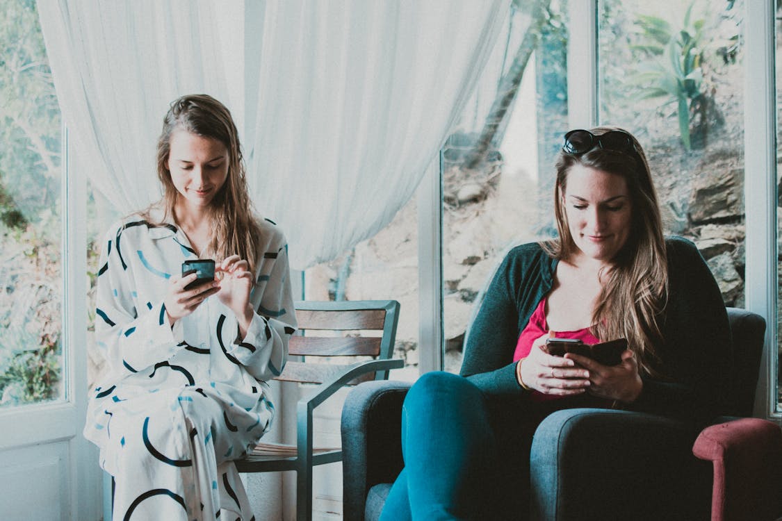 Zwei Frauen, Die Smartphones Im Raum Benutzen