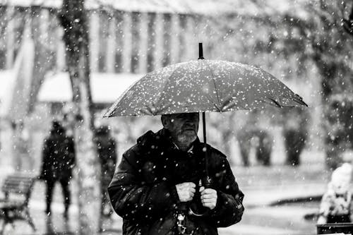 Grayscale Photo of Man Holding an Umbrella