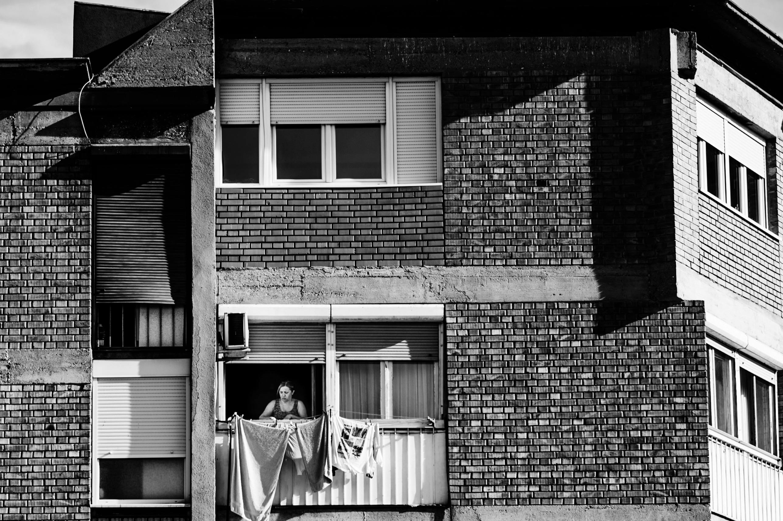 Woman on Balcony in Brick Apartment Building · Free Stock Photo