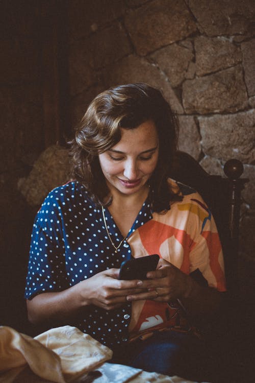 Gratis Wanita Duduk Di Kursi Kayu Saat Menggunakan Smartphone Foto Stok