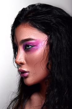 Profile view of a woman with vivid makeup on a white background.