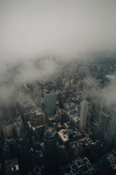A striking aerial photograph of Manhattan, shrouded in clouds, with a moody and dramatic ambiance.