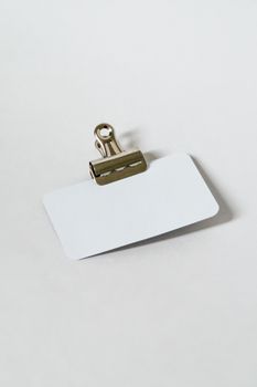 High-angle shot of a blank business card with a metal clip on a white background.