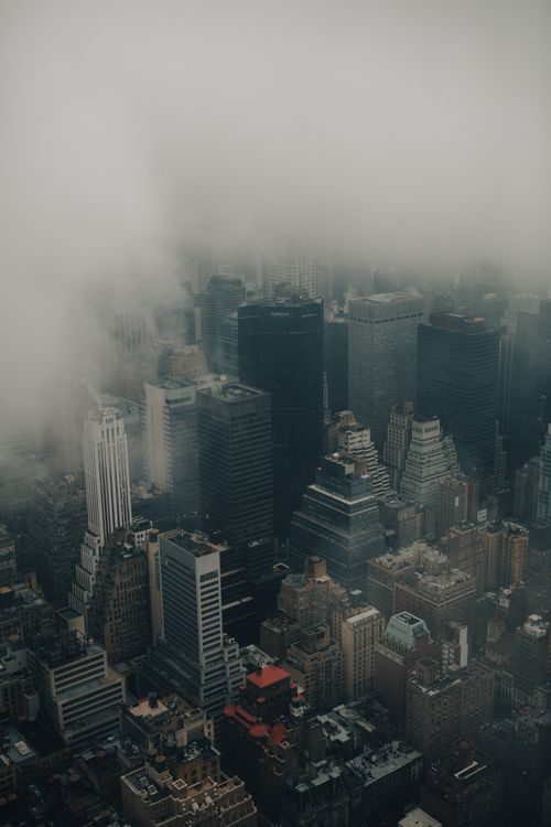 Free Mysterious aerial view of a cityscape shrouded in fog with towering skyscrapers. Stock Photo