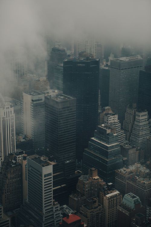 Free A hazy cityscape featuring towering skyscrapers enveloped in fog and smog. Stock Photo