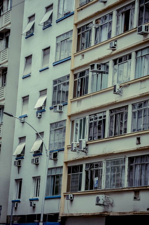 Free Close-up of urban apartment buildings with multiple air conditioners and varied window designs. Stock Photo