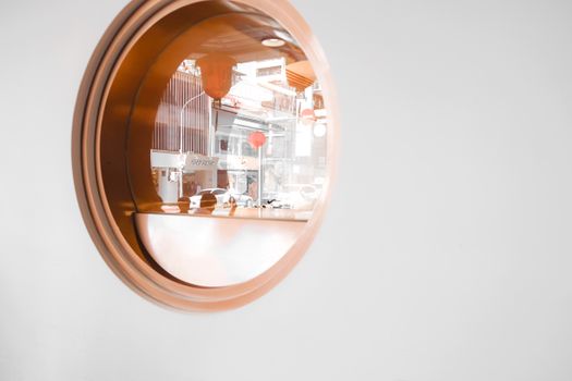 Round window reflecting urban cityscape with minimalistic design and decor elements.