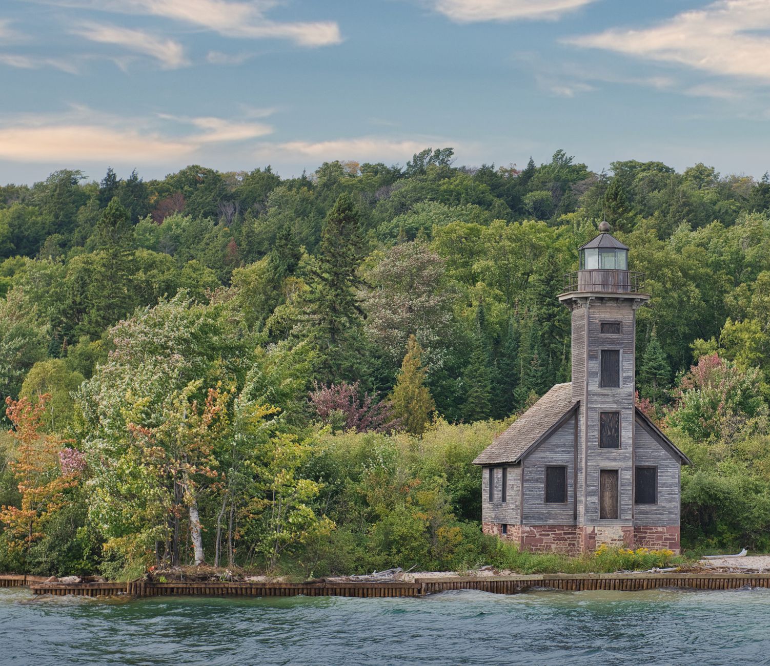 Scenic view of Grand Island Lighthouse surrounded by lush greenery on Lake Superior.