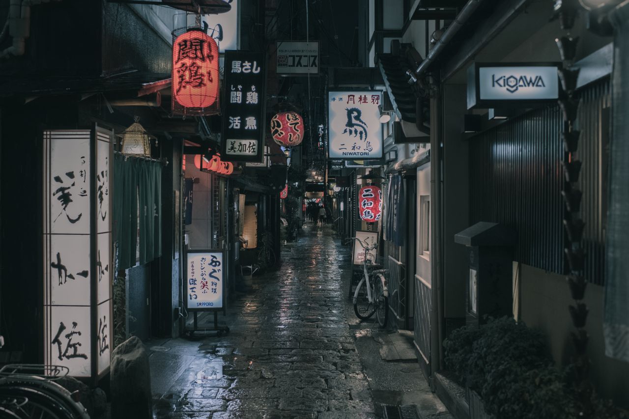 a wet atmospheric street in osaka s shopping district illuminated by t
