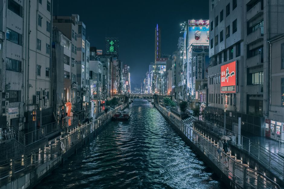 Vibrant night scene of Osaka's canal with illuminated cityscape reflections.