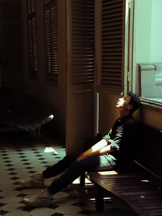 Free Man in Black Top Sitting on Bench Beside of Door Stock Photo