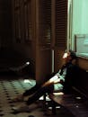 一个年轻人坐在光线昏暗的房间里，沐浴在阳光中，描绘着内省