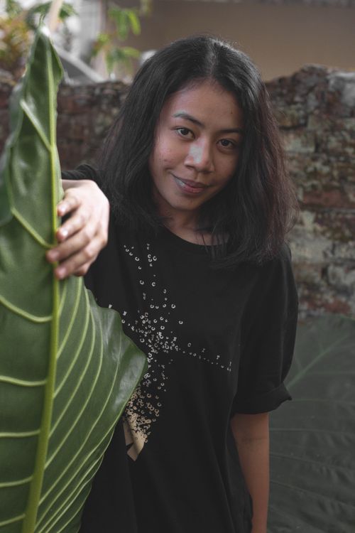 Free A young woman stands outdoors holding a large green leaf, exuding natural beauty. Stock Photo