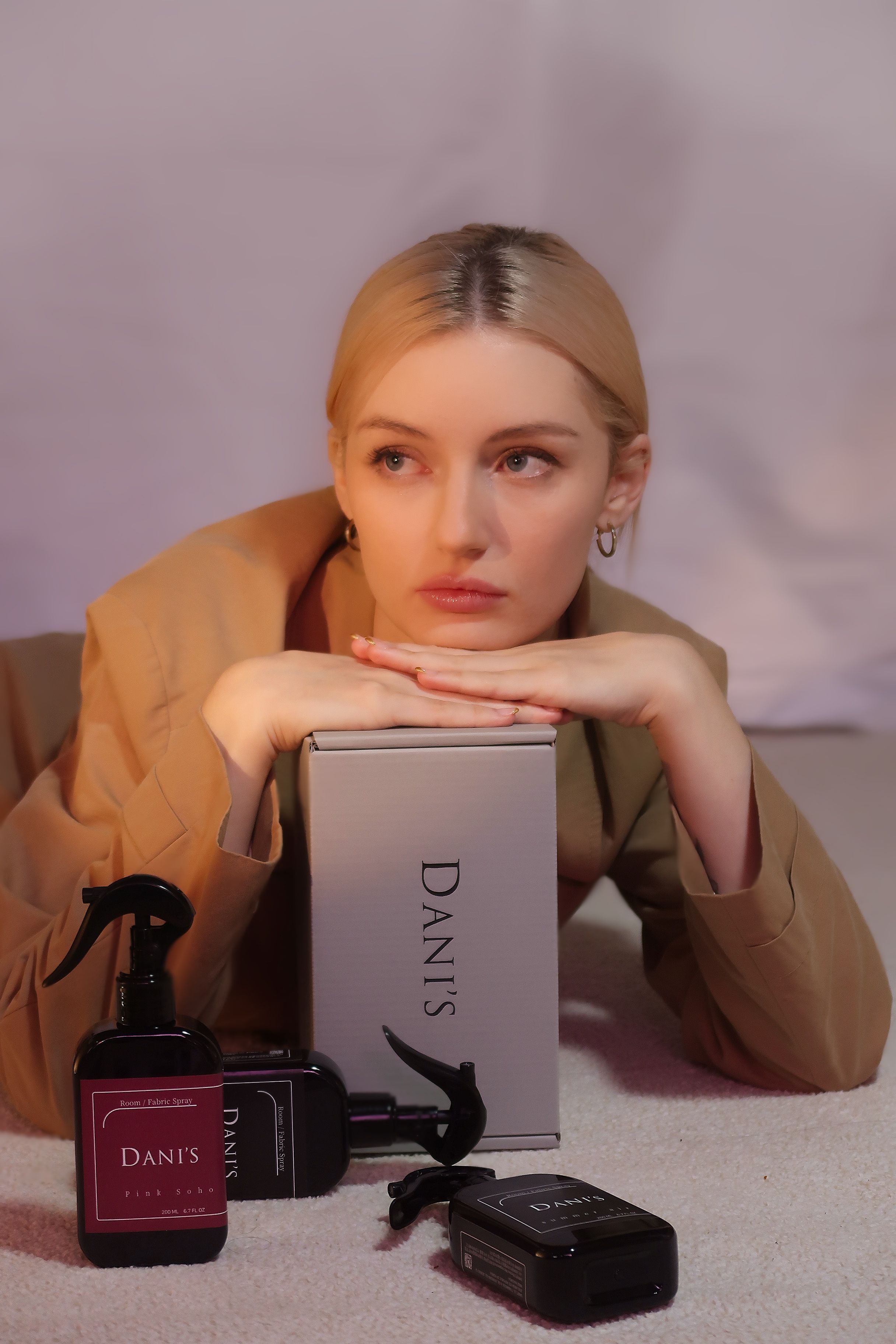 Blonde woman posing with luxury cosmetics in an elegant setting.