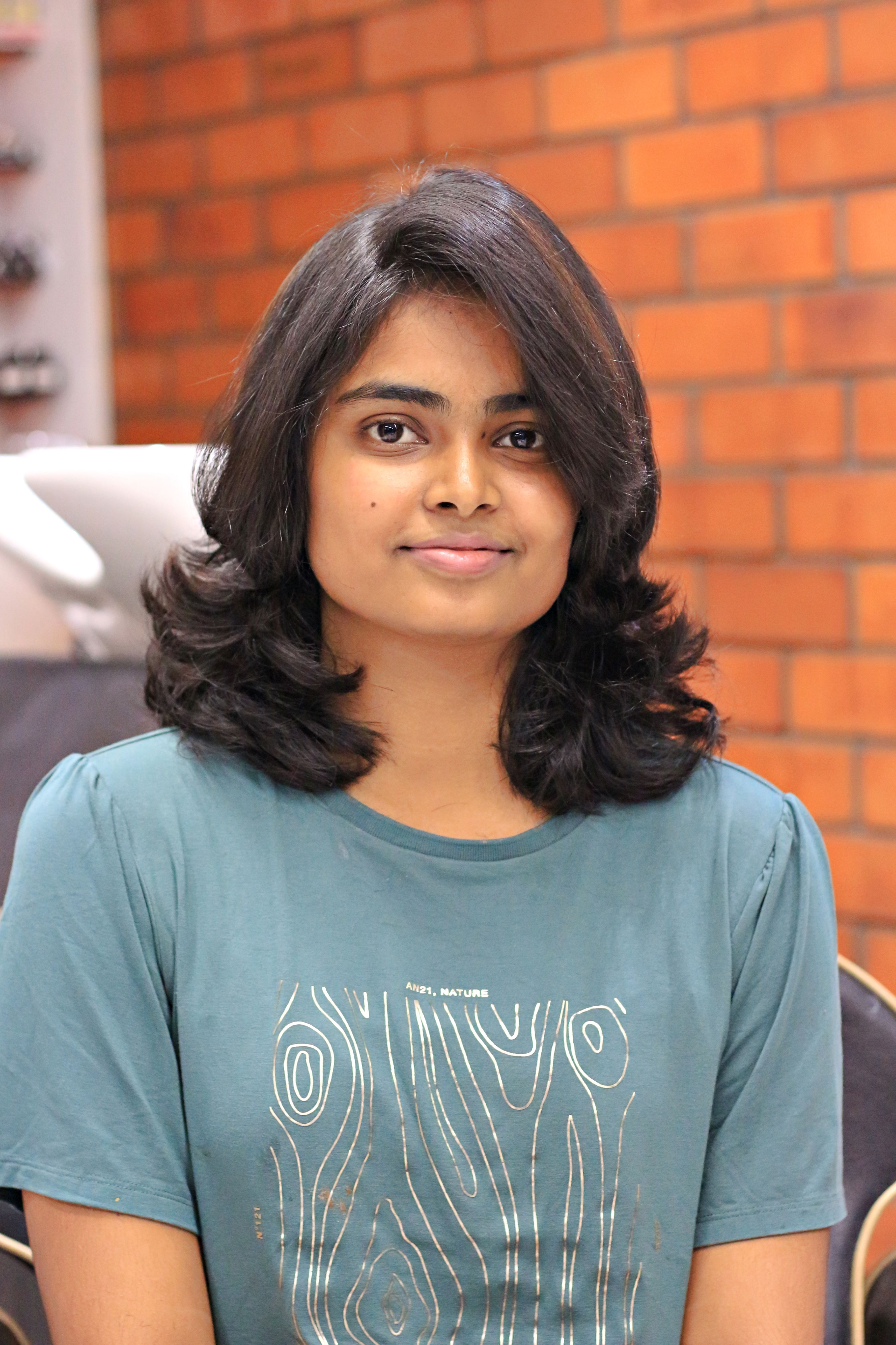 Portrait of a smiling woman with wavy hair in a casual setting, showcasing a relaxed mood and style.