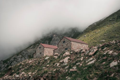 Houses on Hill in Mountains under Clouds