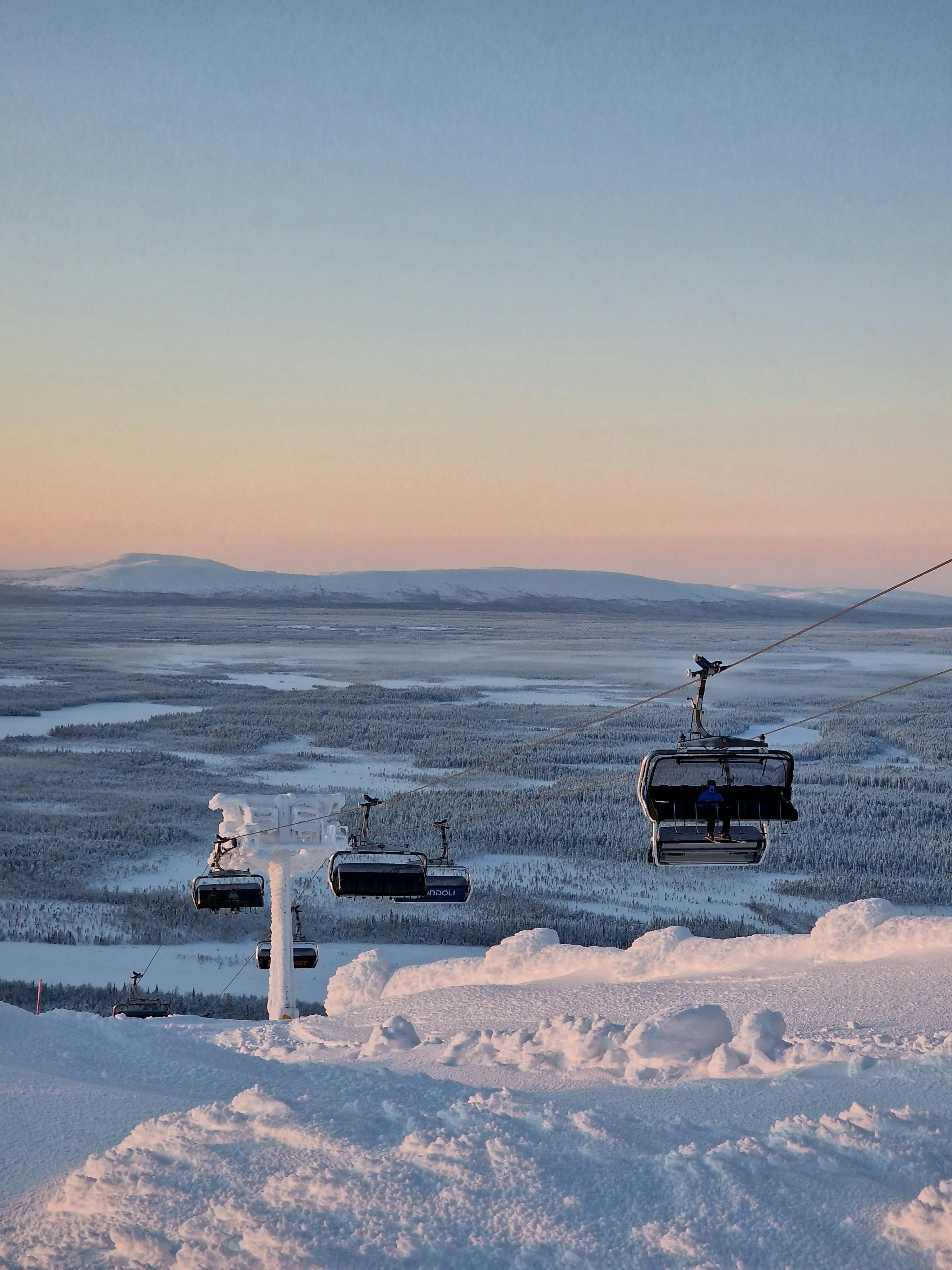 Free Scenic winter landscape featuring cable cars over a snow-covered mountain at sunrise. Stock Photo