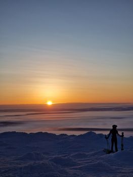 Silhouette of a snowboarder on a snowy mountain slope against a dramatic sunset.