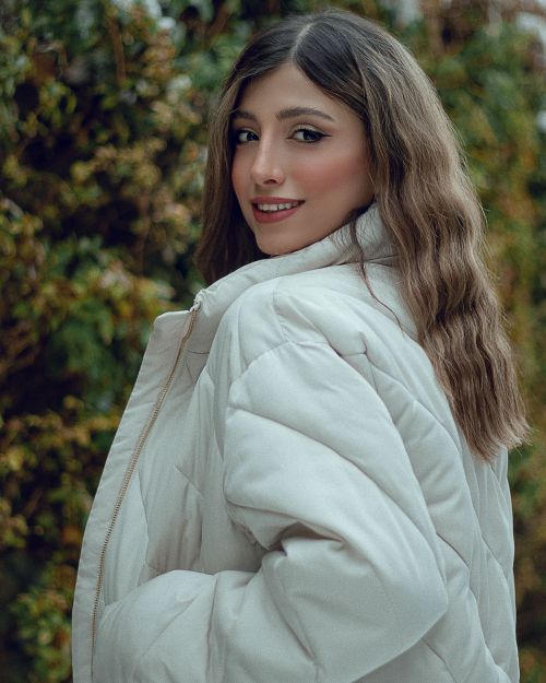 Free Caucasian woman in a white jacket smiling in an outdoor setting. Stock Photo