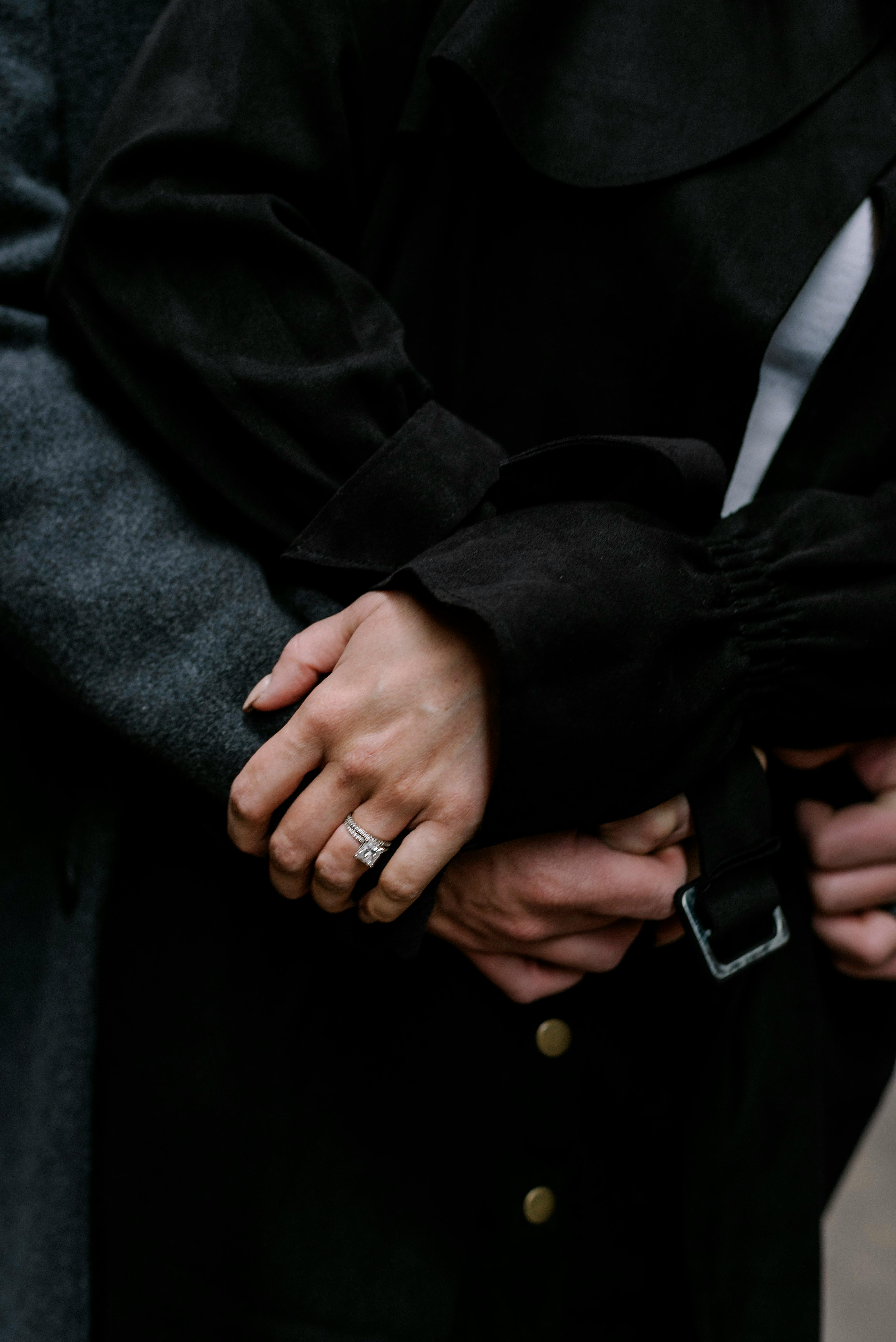 Intimate close-up of a couple embracing, showcasing an engagement ring in focus.
