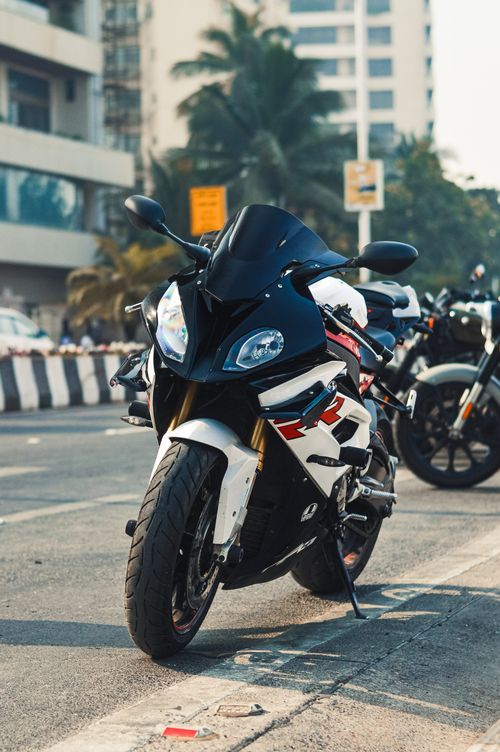 Free A sleek motorcycle parked on a bustling city street in India under clear daylight. Stock Photo
