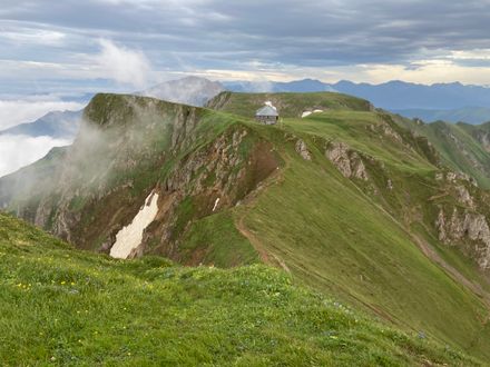 Mountain refuge on a green alpine ridge above the cloud line — Robert Senz on Pexels