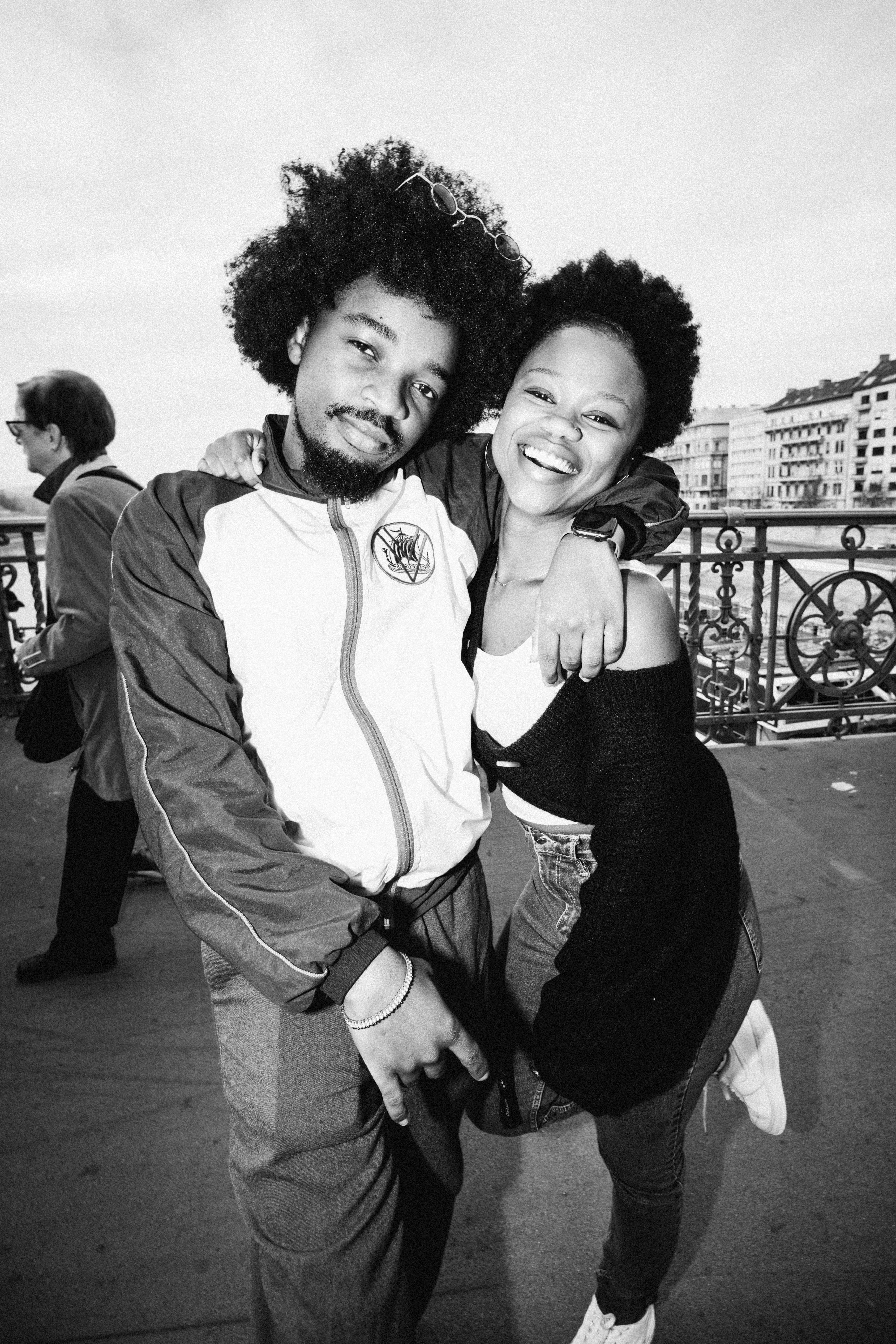 Black and white photo of happy young friends with afro hair on a bridge in Budapest.