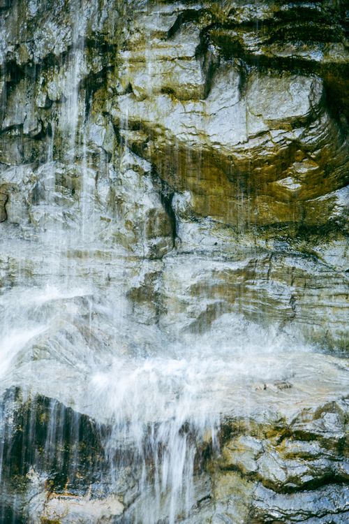 Free A stunning close-up of cascading water over eroded rocks in a tranquil natural setting. Stock Photo