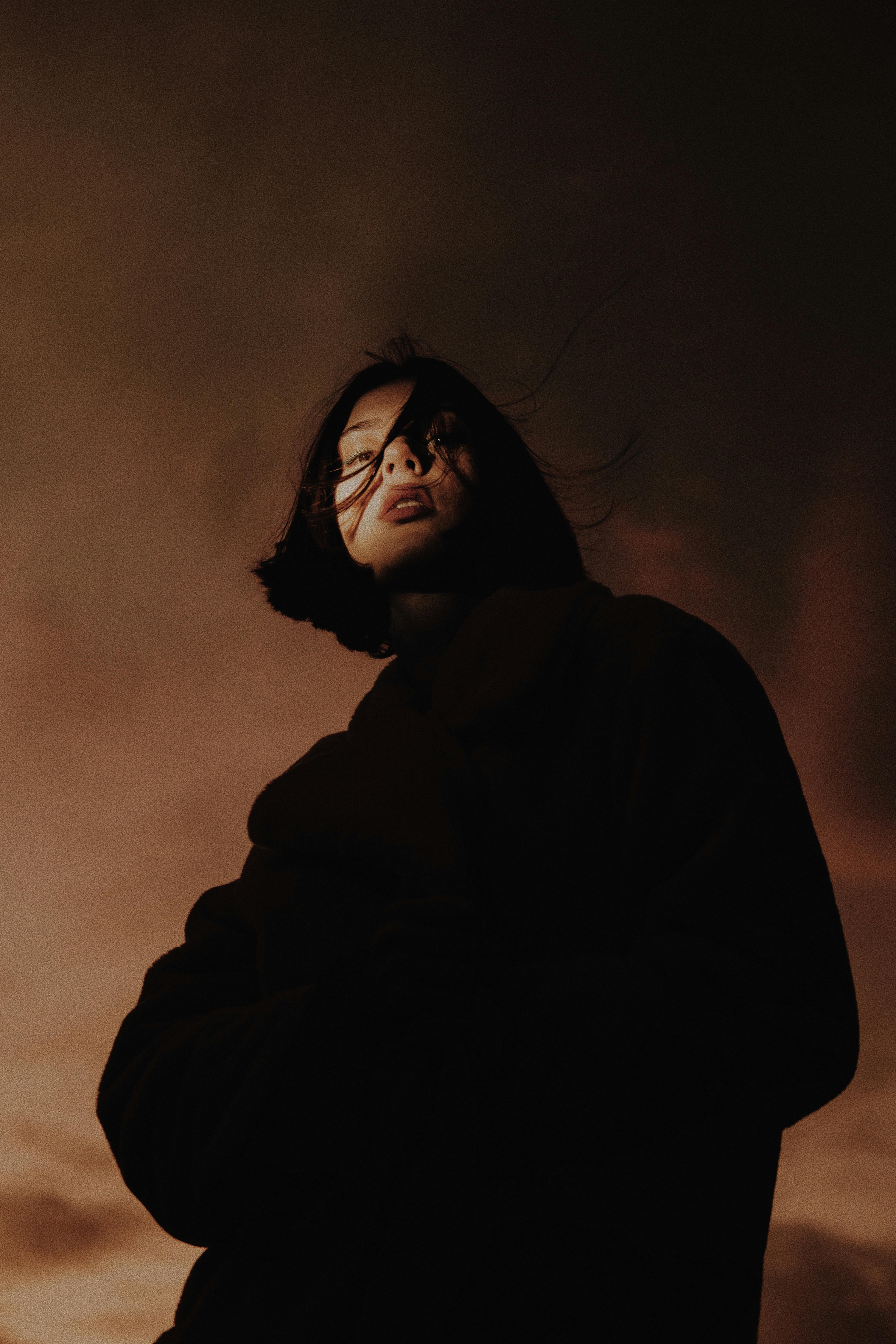 portrait of a young woman standing against clouds at dusk