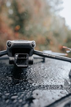 A detailed close-up of a drone resting on a rain-soaked surface against a blurred natural background.