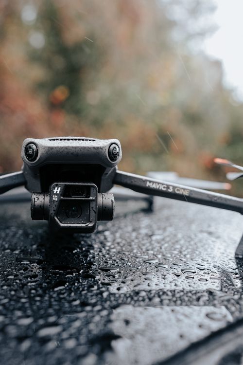 Free A detailed close-up of a drone resting on a rain-soaked surface against a blurred natural background. Stock Photo