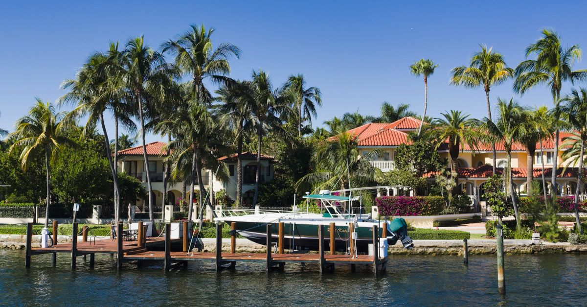 Scenic view of luxury waterfront homes with palm trees and a boat docked in Fort Lauderdale, Florida.
