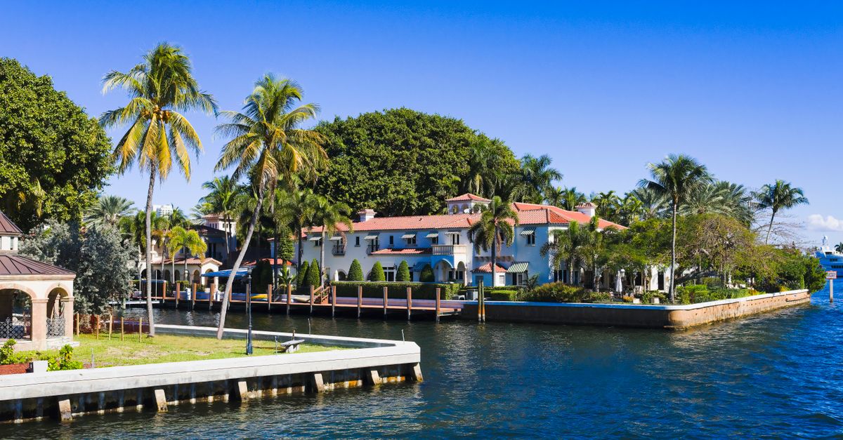 Beautiful tropical homes along a canal with palm trees and clear blue sky in Fort Lauderdale, Florida.